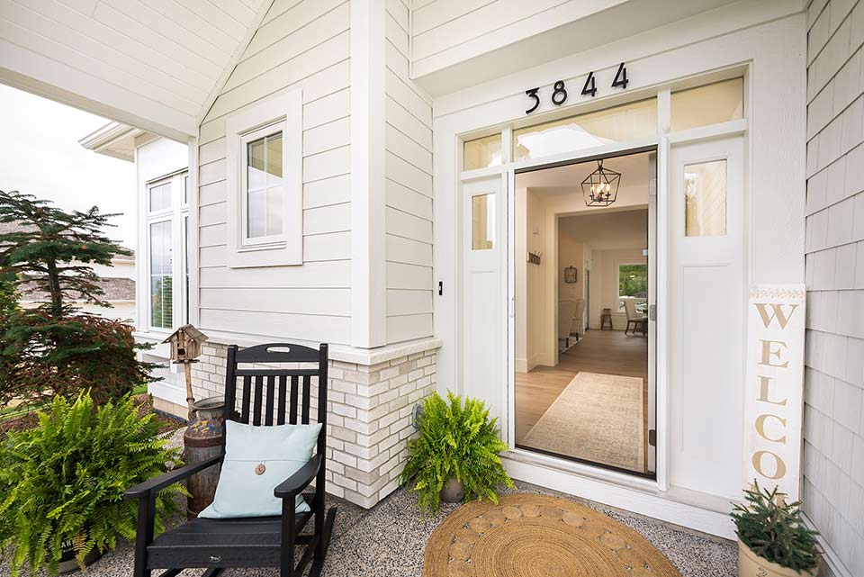 Front entry with open retractable screen door, welcoming decor, and a view into a bright, modern home interior.