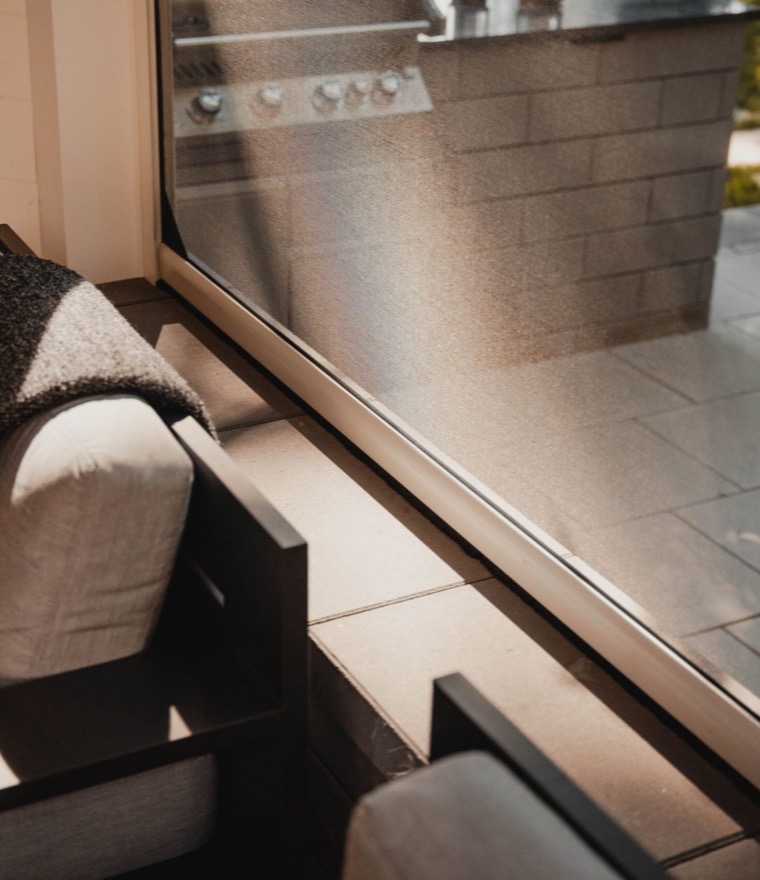 Close-up of solar protection mesh on a patio screen, with an outdoor kitchen and lounge seating visible through it