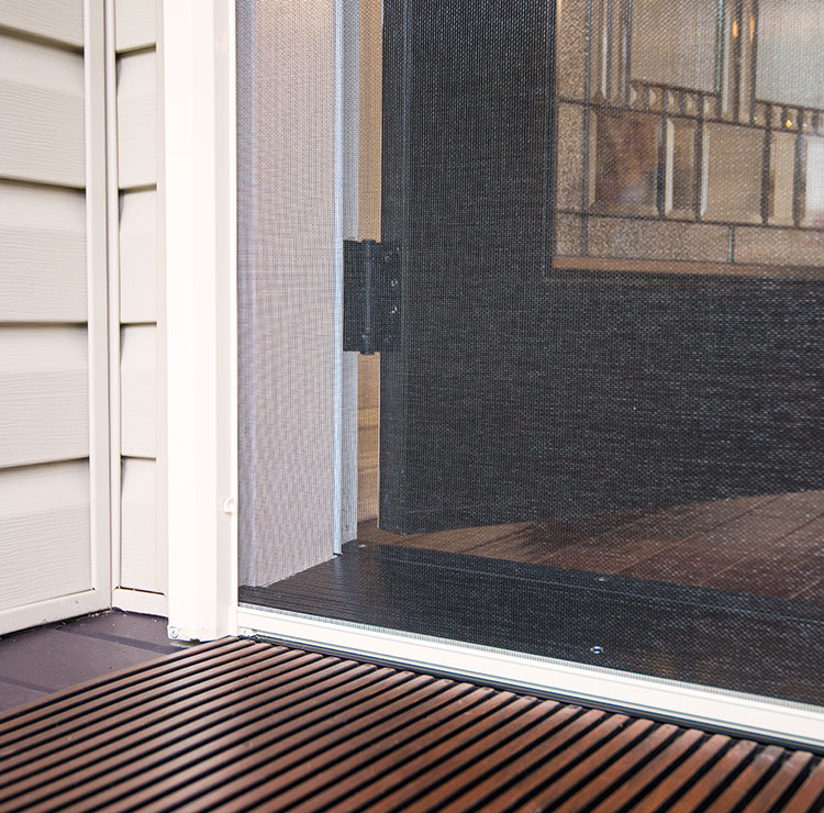 Close-up view of a retractable screen door housing, partially extended across a patio entrance.