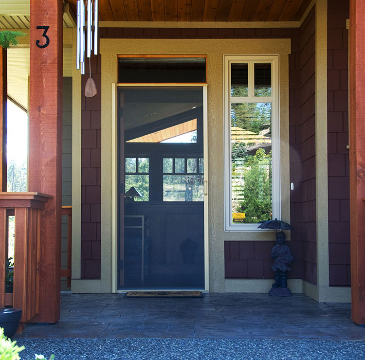 Covered porch entrance with a dark screen door drawn across the front door frame, blending with the exterior.
