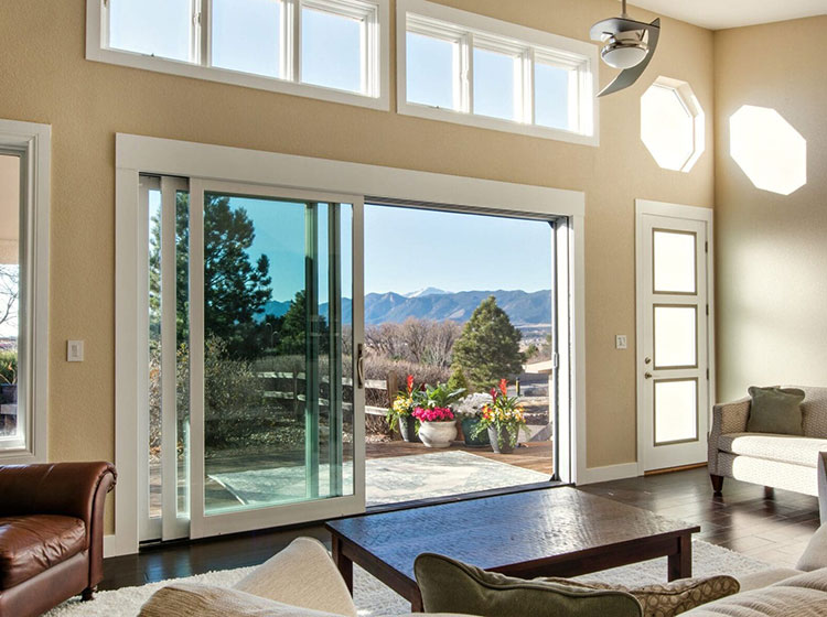 Bright living room with large multi-panel sliding glass door system offering panoramic mountain views, complemented by clerestory windows above