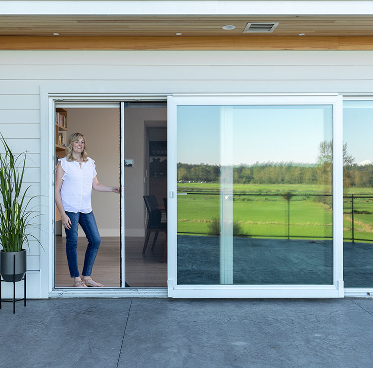 Modern sliding glass door system with retractable screen, opening to patio with golf course views