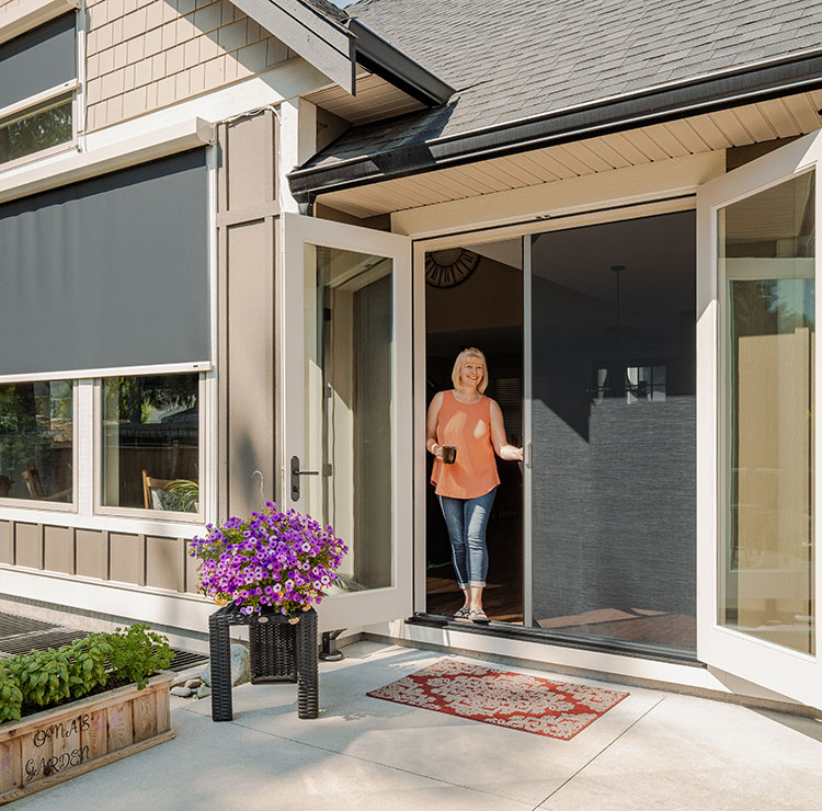 Craftsman-style front entry with retractable screen door, featuring purple flowers and exterior solar shade