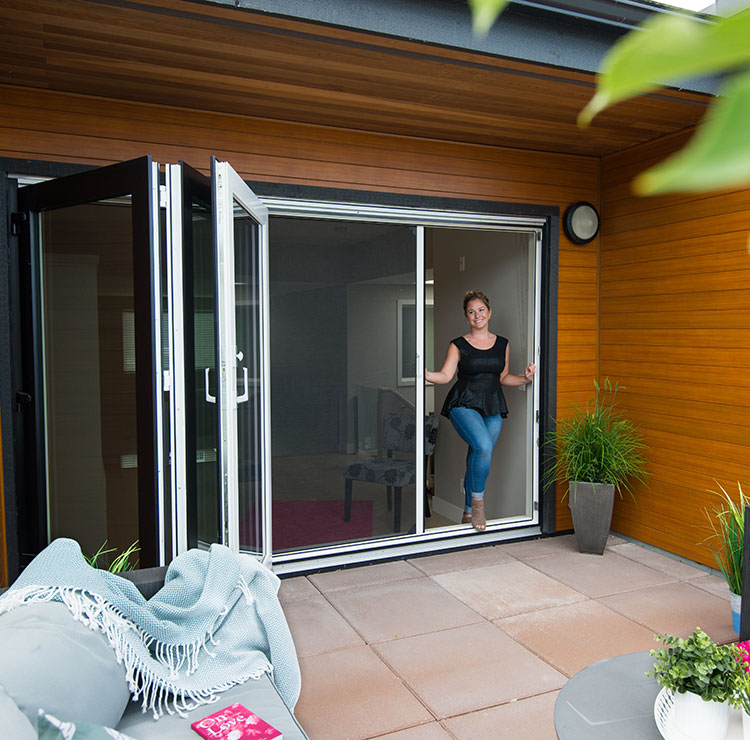 Contemporary patio with bi-fold glass doors, cedar plank ceiling, and retractable screens leading to outdoor dining