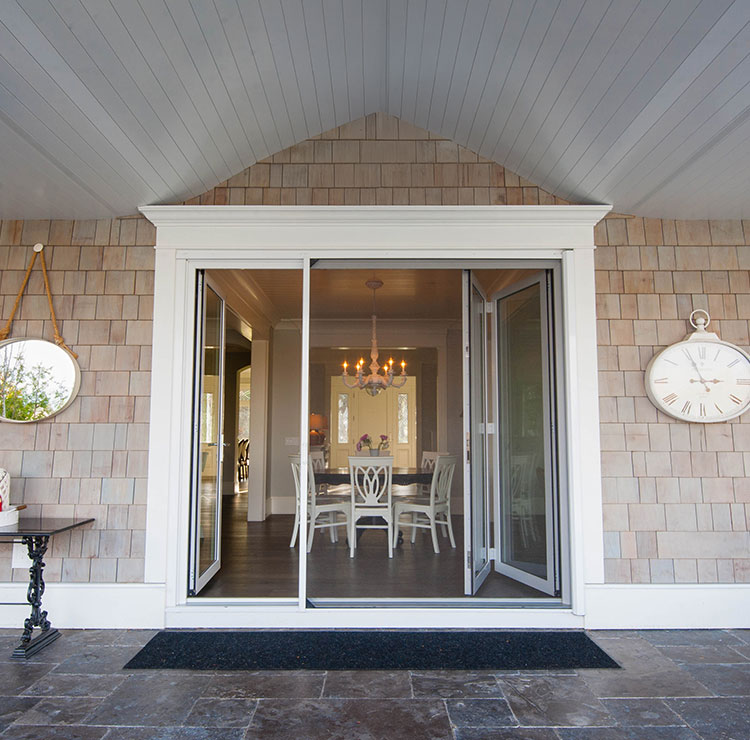 Elegant coastal home entry with sliding screen doors, decorative clocks, and shingle siding