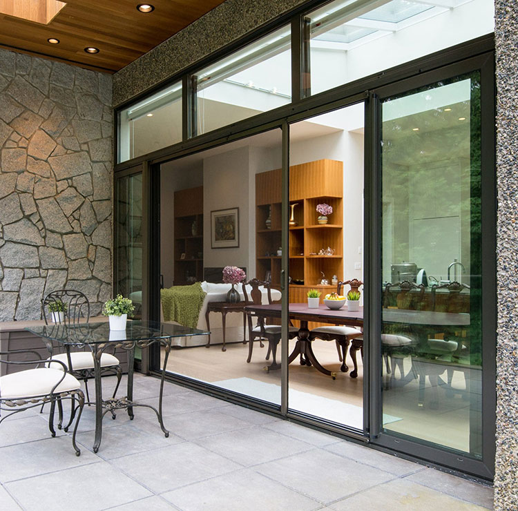 Stone-walled patio with sliding glass doors, wrought iron dining set, and built-in wooden display shelving inside