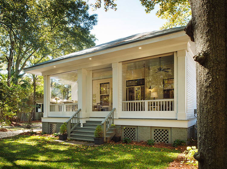 Southern-style porch with retractable screens, white columns, and comfortable seating creating an inviting indoor-outdoor living space