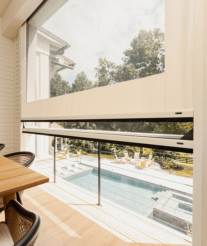 Screened porch with retractable vinyl panels overlooking pool area and outdoor entertainment space