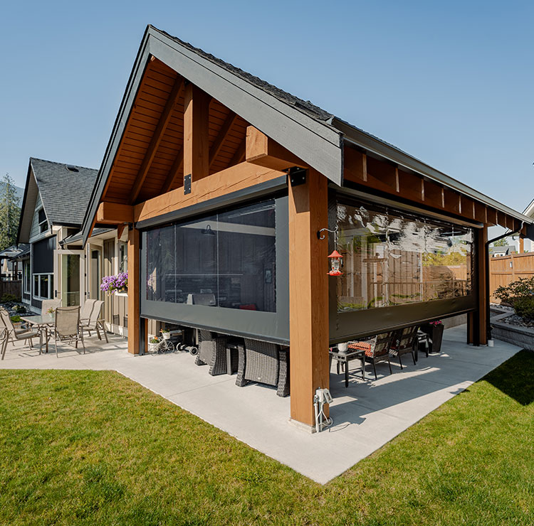 Timber-framed pergola with retractable screens creating sheltered outdoor living space, featuring wicker furniture