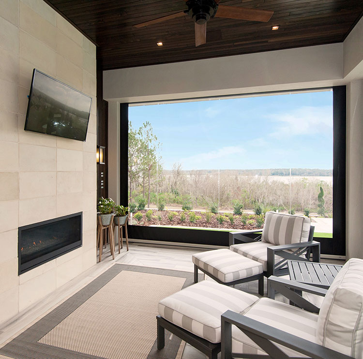 Screened porch with fireplace and lounge chairs, luxury vinyl panels providing unobstructed views of landscaped yard