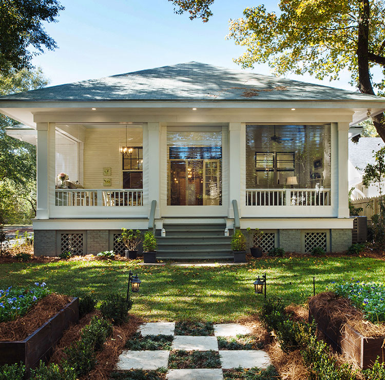 Southern-style porch with clear vinyl screens, white columns, and traditional rocking chairs in evening light