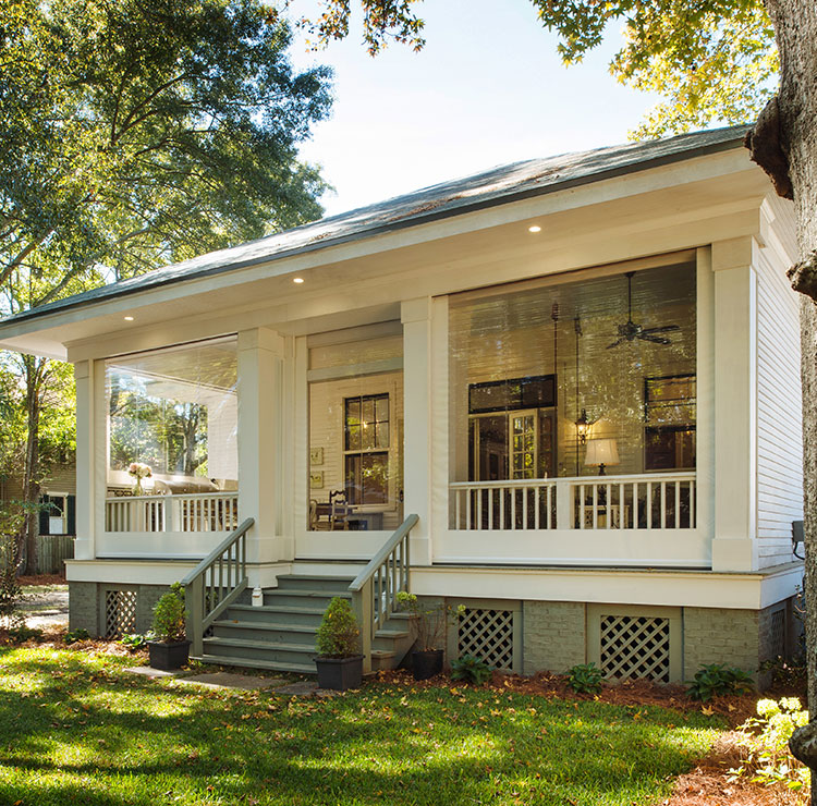 Southern-style porch with clear vinyl screens, white columns, and traditional rocking chairs in evening light