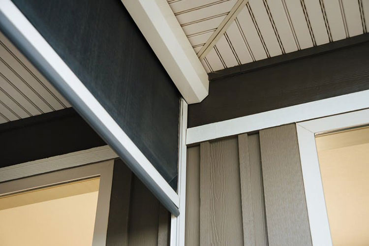 Detail view of surface-mounted screen track and housing on home exterior with partially lowered screen