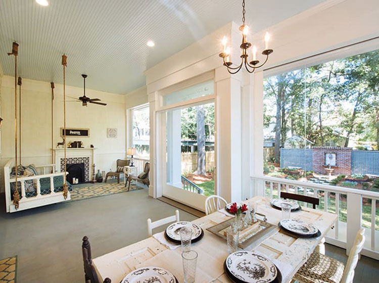 Screened porch with dining table, hanging swing, and fireplace