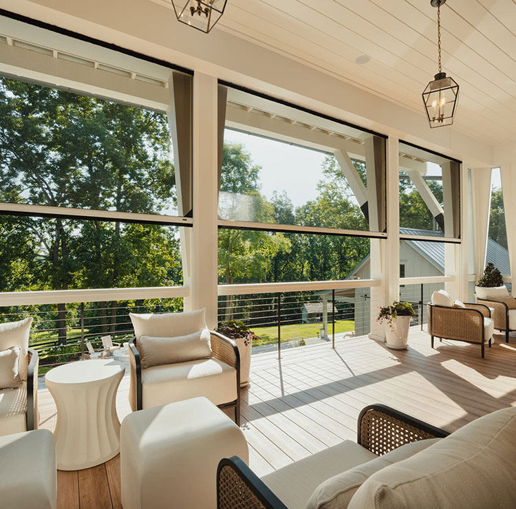 Elegant covered porch with white furniture and lantern lighting, featuring motorized screens with tree views