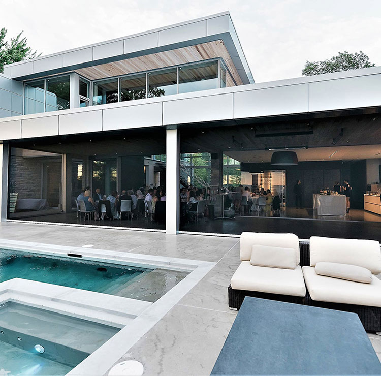 Modern poolside entertainment space with dark motorized screens, protecting indoor dining area
