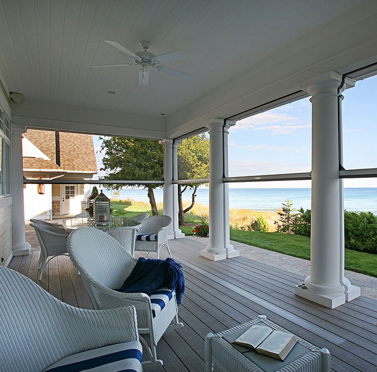 Coastal porch with white columns and motorized screens, overlooking beach and ocean views