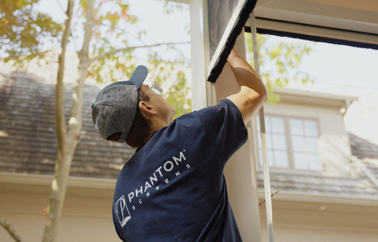 Installer adjusting a retractable screen in a doorway