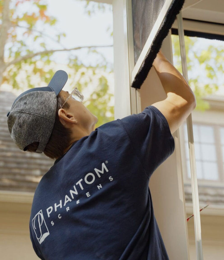 Installer reaching up to adjust a retractable screen on a door frame