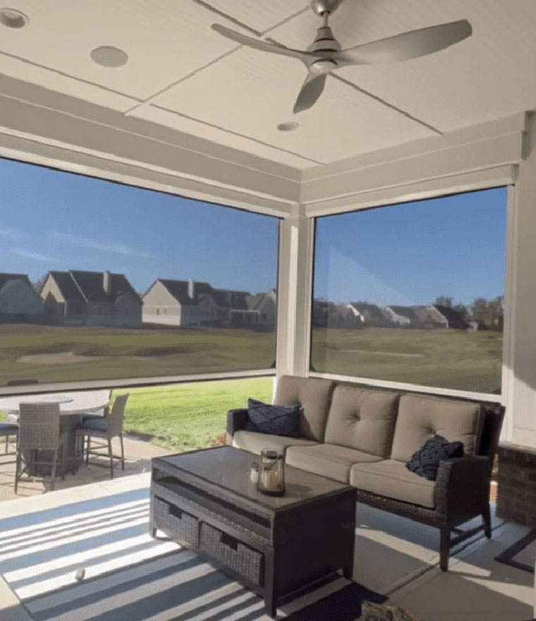 Covered porch with outdoor seating and retractable screens overlooking a neighborhood