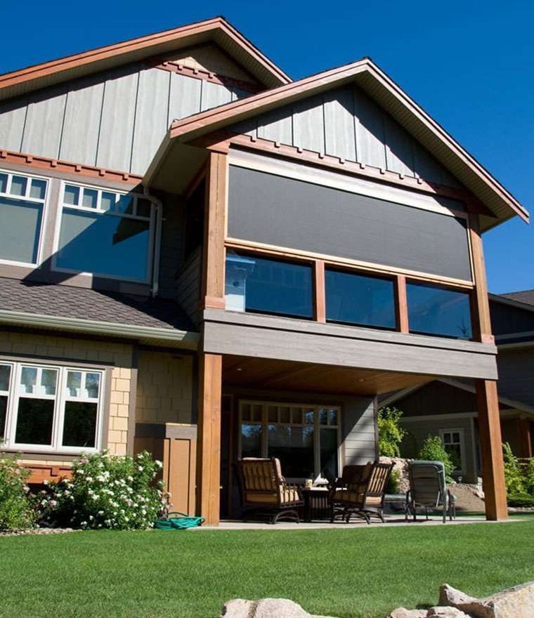 Two-story home with solar screens on the upper balcony and covered patio below
