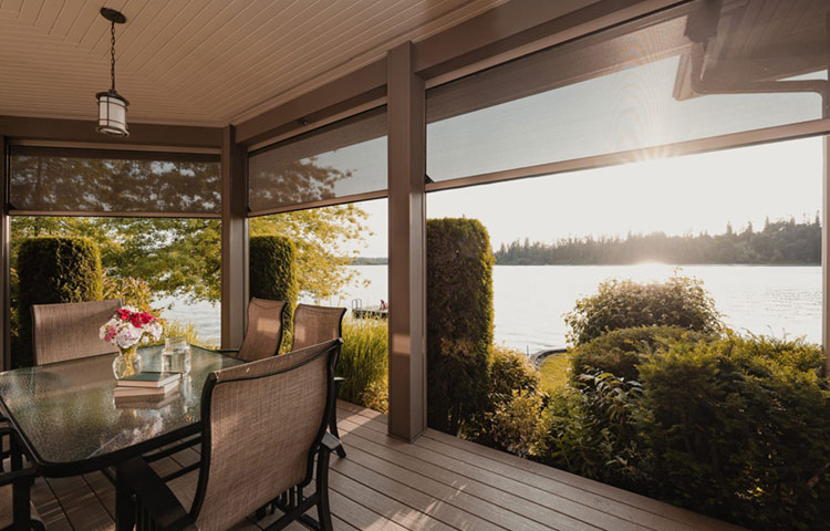 Screened porch with dining table overlooking a lake at sunset
