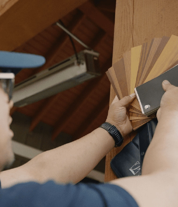 Person holding fan of wood grain color swatches near a screen housing