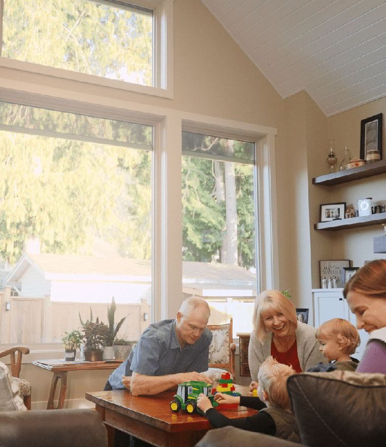 Multigenerational family playing together in a bright living room with large windows