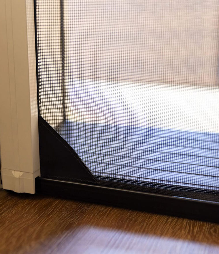 Close-up of screen mesh and black bottom track on hardwood floor