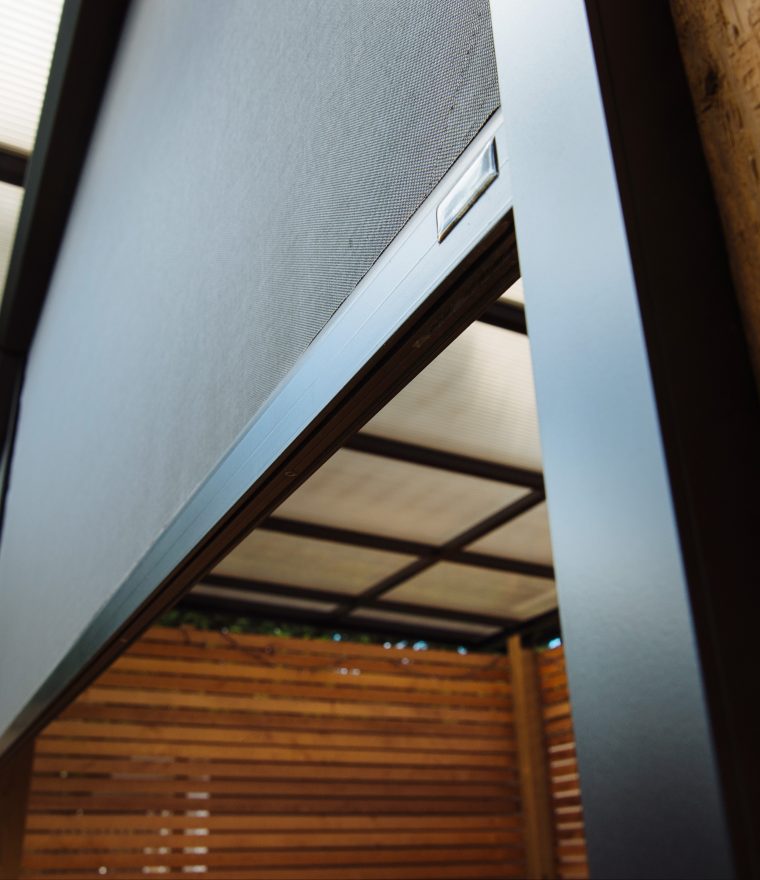 close-up of a black motorized custom solar screen enclosing an outdoor deck space