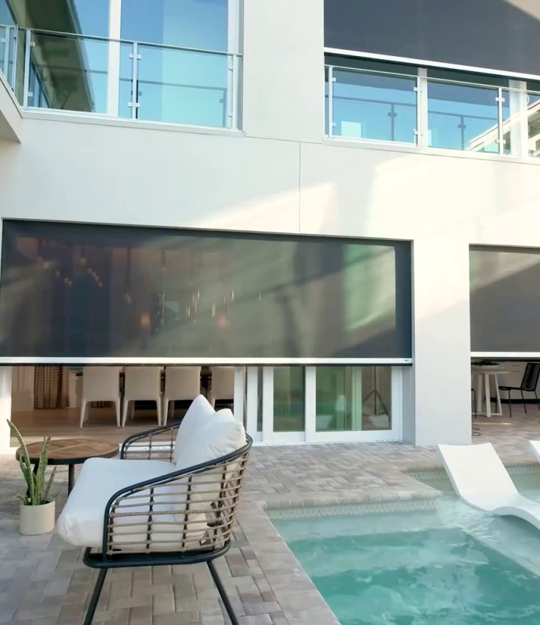 an outdoor pool area in a condo courtyard with solar mesh screens protecting a dining area.