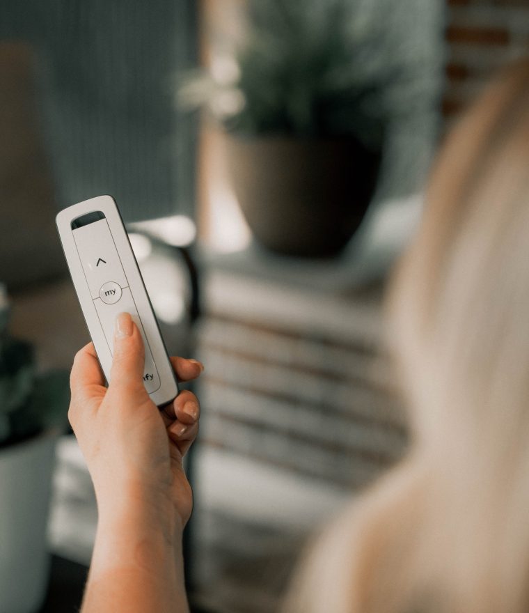 a person holding a Somfy® motorized retractible screen controller in their hand