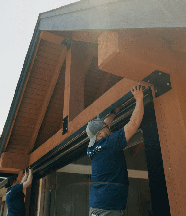 Installers mounting screen housing on covered patio