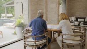 A man and woman seated at a table beside a pool
