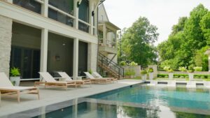 A serene pool with lounge chairs positioned in front of a modern house